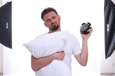 Photo of Unhappy man with pillow on white background. Insomnia problem