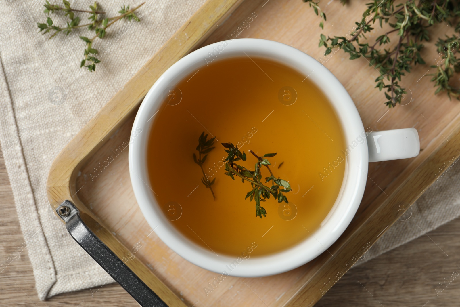 Photo of Cup of fresh thyme tea on wooden table, flat lay