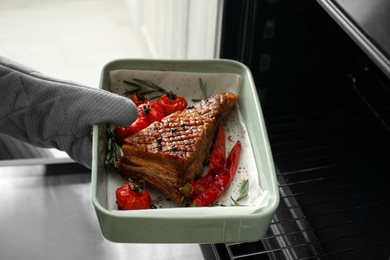 Chef taking delicious roasted ribs out of oven, closeup