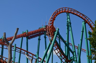 Amusement park. Beautiful large colorful rollercoaster against blue sky, low angle view