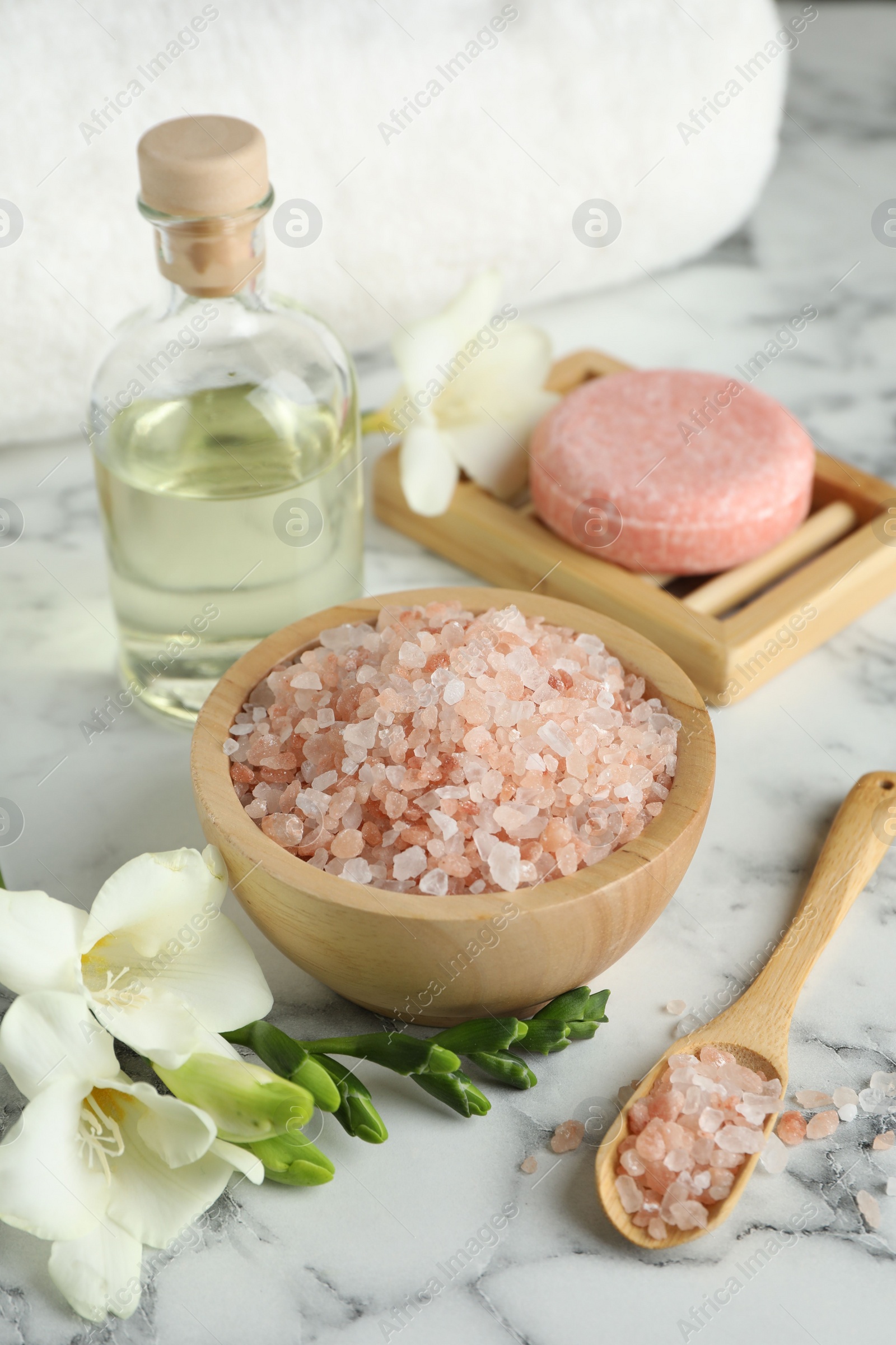 Photo of Beautiful spa composition with sea salt, soap bar, essential oil and flowers on white marble table