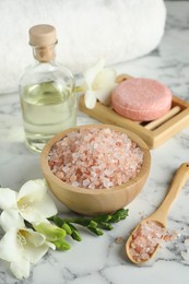 Photo of Beautiful spa composition with sea salt, soap bar, essential oil and flowers on white marble table