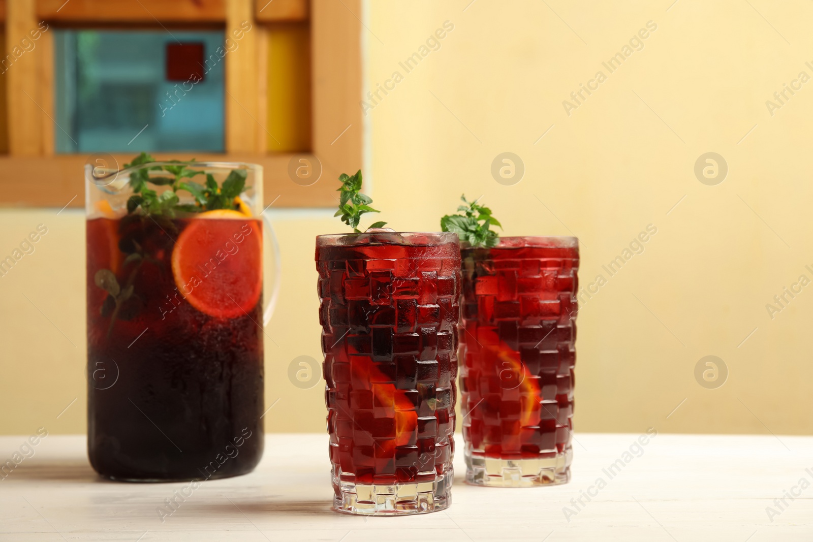 Photo of Glasses and jug with delicious refreshing cocktail on table