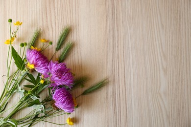 Bouquet of beautiful wildflowers on wooden table, top view. Space for text