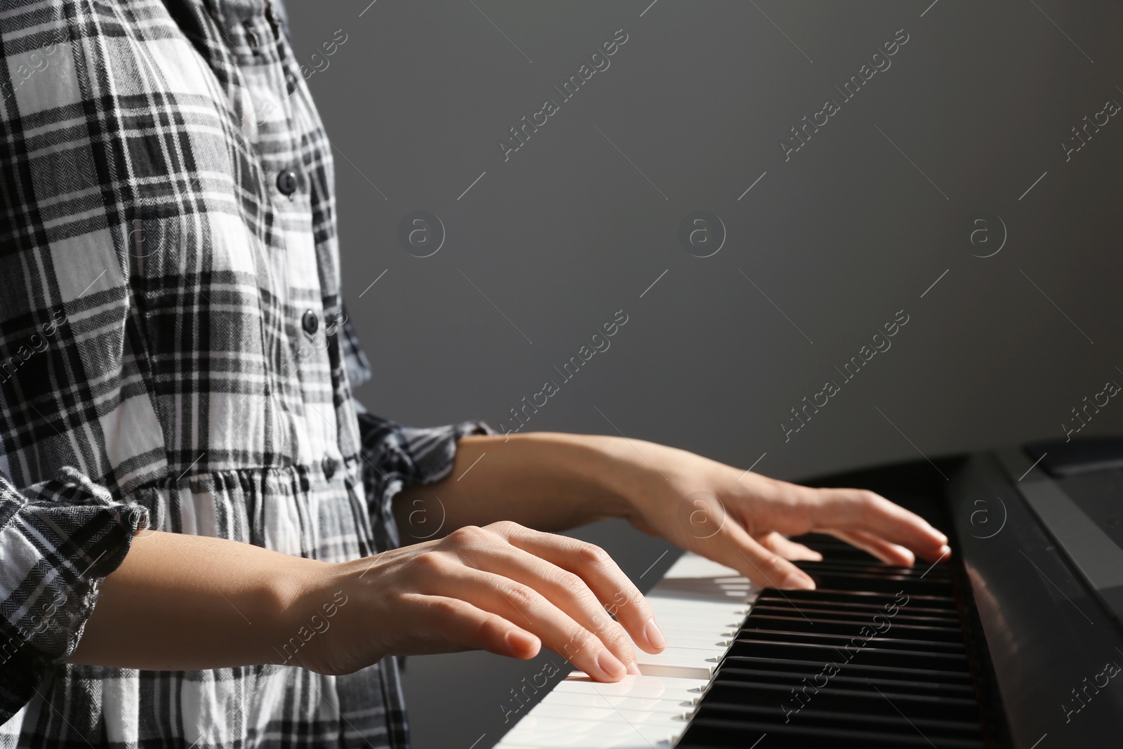 Photo of Young woman playing piano against grey background, closeup