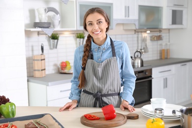 Professional female chef standing near table in kitchen