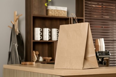 Photo of Paper bag on wooden counter in cafe, space for text