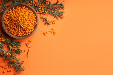 Photo of Fresh ripe sea buckthorn on orange background, flat lay. Space for text
