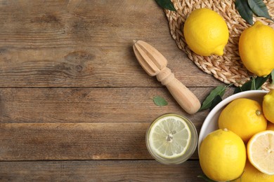Photo of Squeezer with lemons on wooden table, flat lay. Space for text