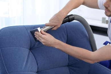 Dry cleaning worker removing dirt from armchair indoors