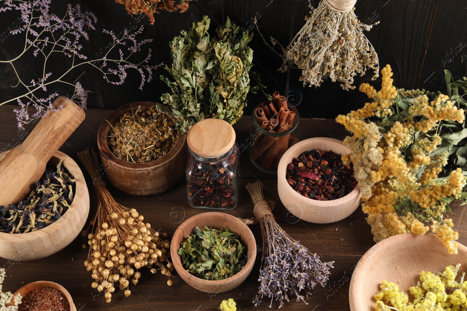 Photo of Many different dry herbs and flowers on wooden table, above view