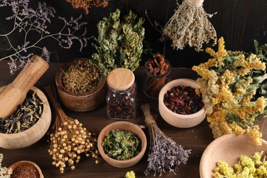 Many different dry herbs and flowers on wooden table, above view