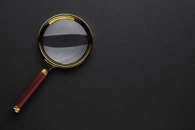 Photo of Magnifying glass on dark background, top view. Space for text