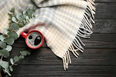 Flat lay composition with hot drink and warm plaid on black wooden table