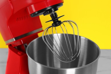 Photo of Closeup view of modern red stand mixer on yellow background