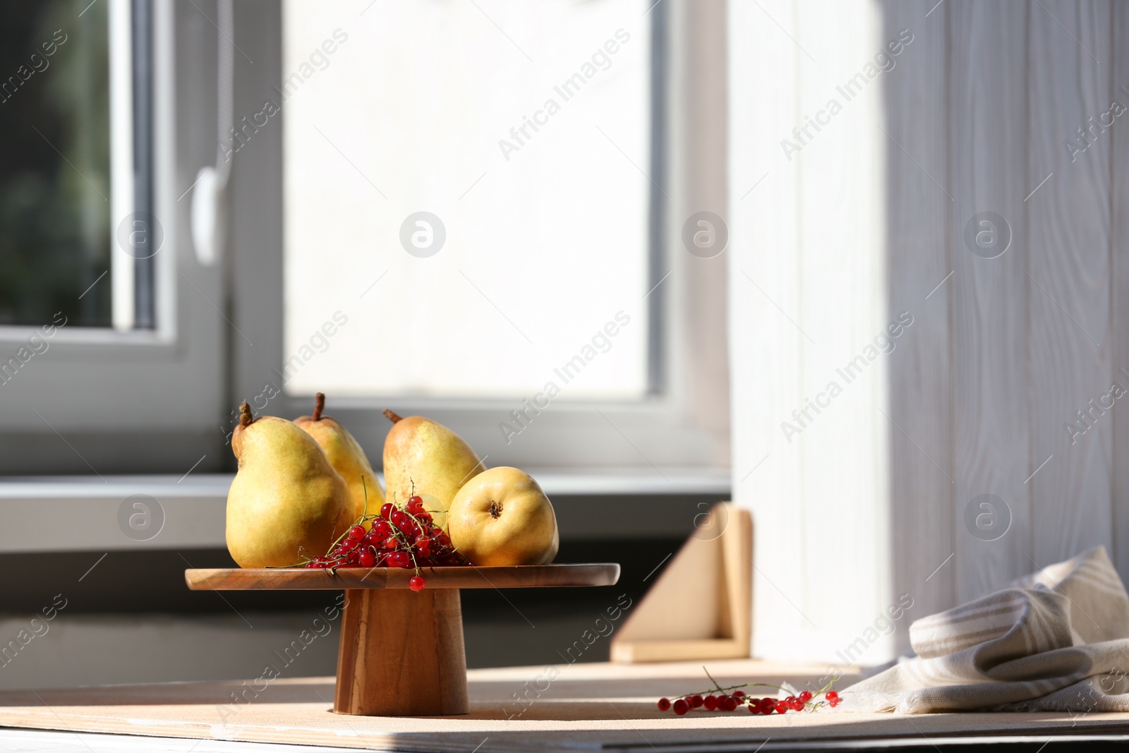 Photo of Stand with juicy pears, red currants and double-sided backdrop on table in photo studio. Space for text