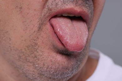 Man showing his tongue on grey background, closeup