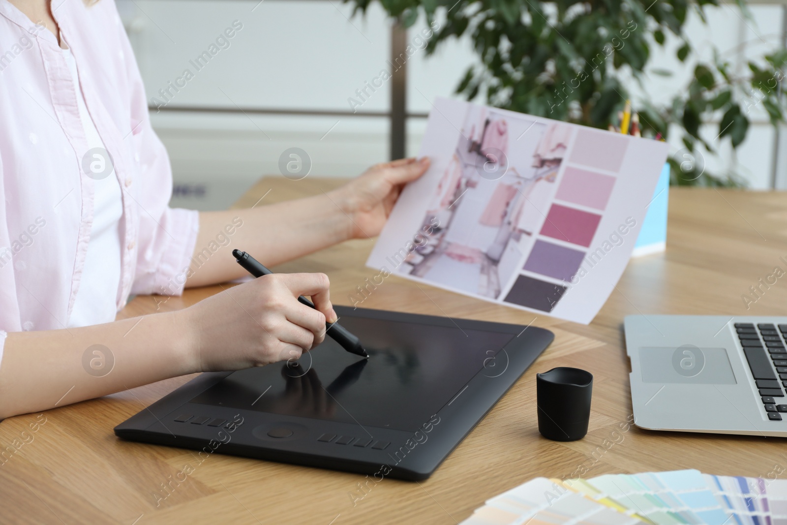 Photo of Professional designer with graphic tablet at wooden table, closeup