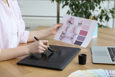 Professional designer with graphic tablet at wooden table, closeup