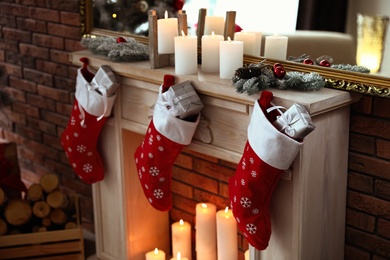 Decorative fireplace with Christmas stocking and gifts in stylish room interior