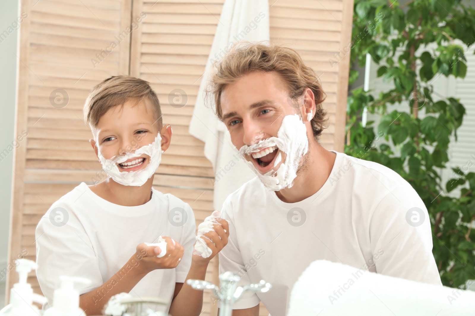 Photo of Father and son with shaving foam on faces in bathroom