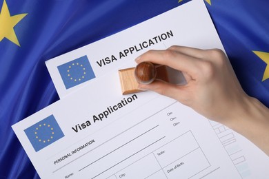 Immigration to European Union. Woman stamping visa application forms on flag, top view