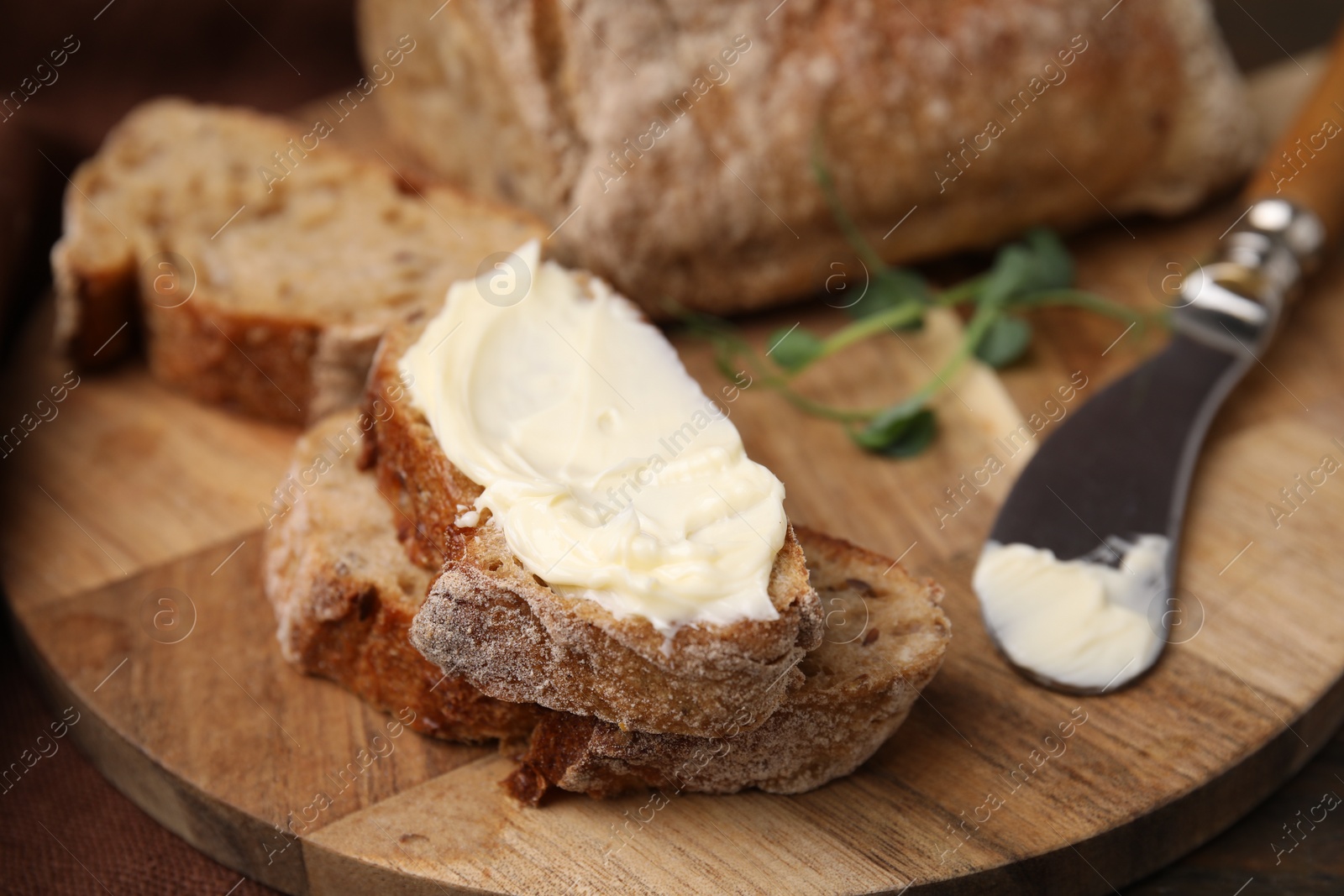 Photo of Slices of tasty bread with butter and knife on wooden board, closeup, Space for text