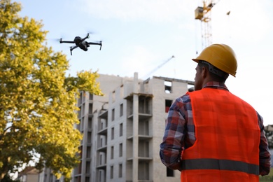 Photo of Builder operating drone with remote control at construction site. Aerial survey