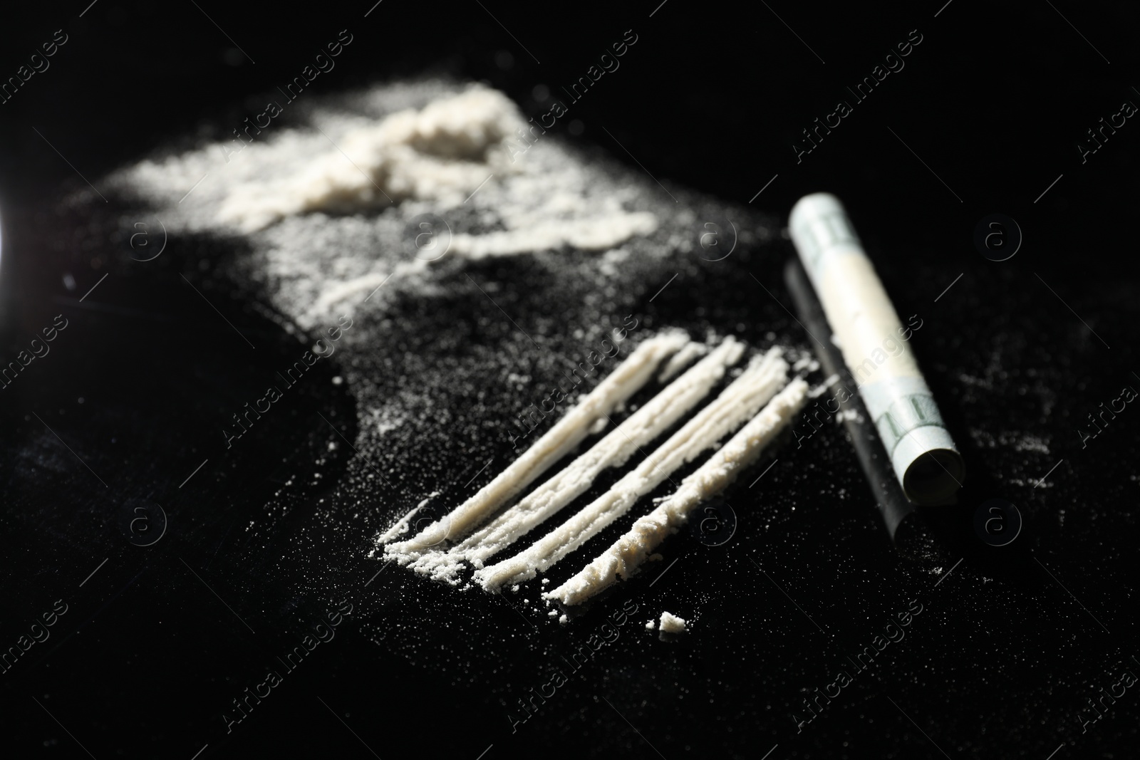 Photo of Drug addiction. Cocaine and rolled dollar banknote on black table, selective focus