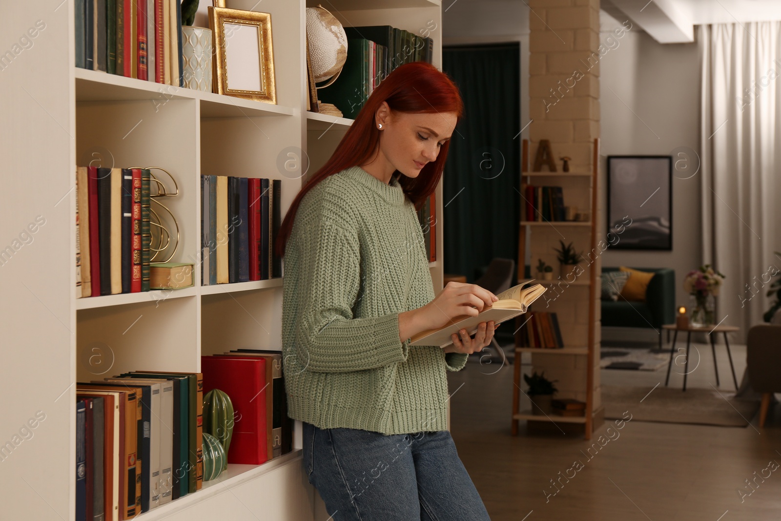 Photo of Beautiful young woman reading book in room. Home library