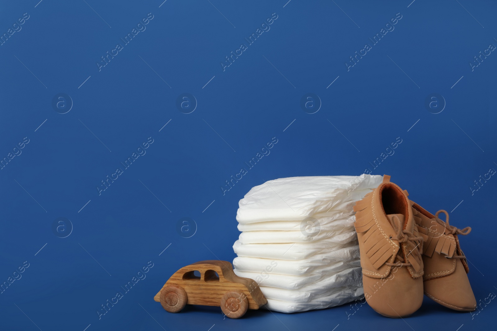 Photo of Diapers, baby accessories and toy car on blue background. Space for text
