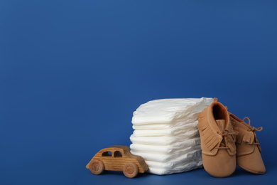 Diapers, baby accessories and toy car on blue background. Space for text