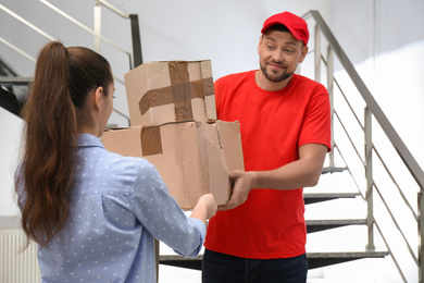 Emotional courier giving damaged cardboard boxes to client indoors. Poor quality delivery service