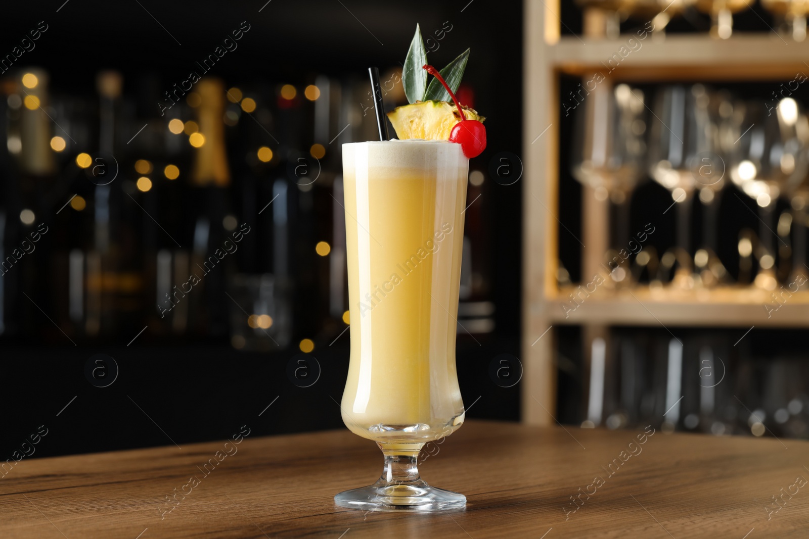 Photo of Tasty Pina Colada cocktail on wooden bar countertop