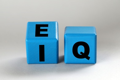 Photo of Blue cubes with letters E, I and Q on light grey background