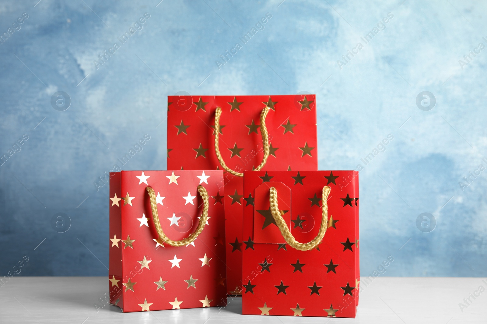 Photo of Red shopping paper bags with star pattern on white table