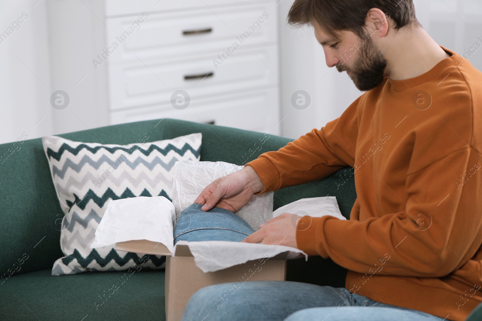 Photo of Man opening parcel at home. Internet shopping