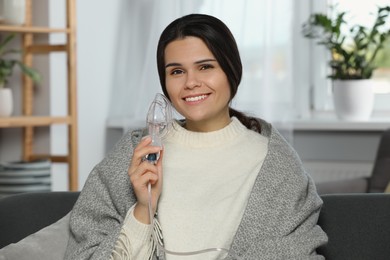 Happy young woman with nebulizer at home