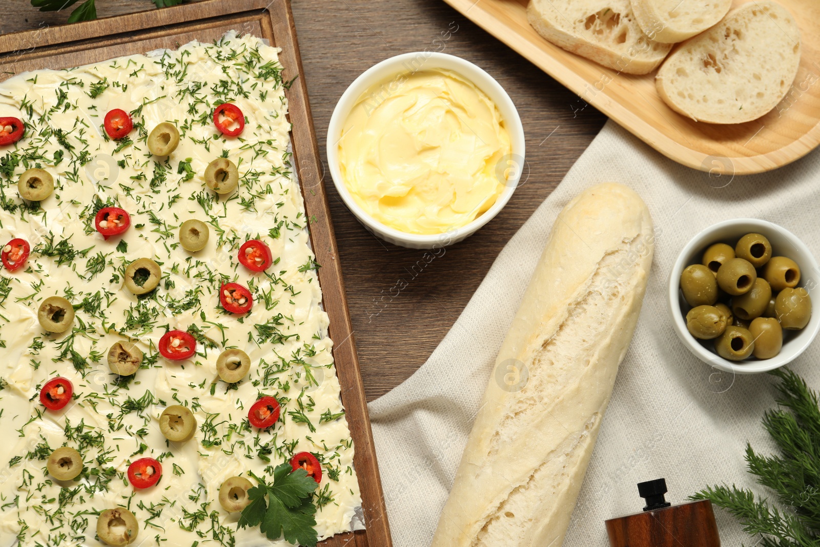 Photo of Fresh natural butter board with olives, pepper and bread on wooden table, flat lay