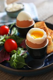 Delicious breakfast with soft boiled eggs served on wooden table, closeup