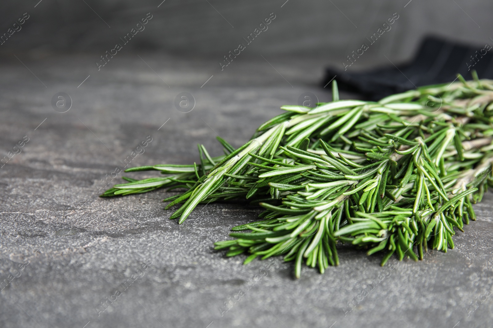 Photo of Bunch of fresh rosemary on grey table, space for text