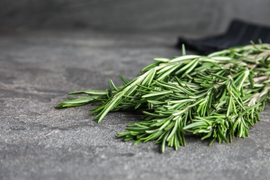 Bunch of fresh rosemary on grey table, space for text