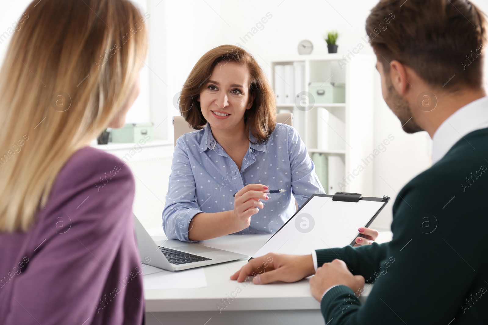 Photo of Real estate agent consulting young couple in office