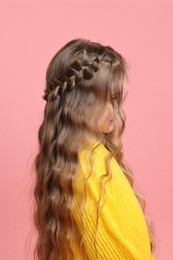 Photo of Cute little girl with braided hair on pink background