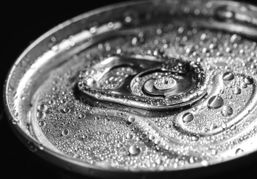 Aluminum can of beverage covered with water drops on black background, closeup