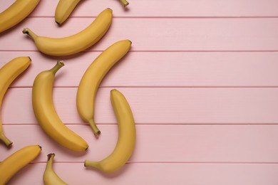 Ripe yellow bananas on light pink wooden table, flat lay. Space for text