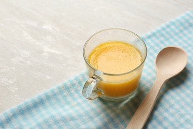 Photo of Glass cup with clarified butter and wooden spoon on table. Space for text