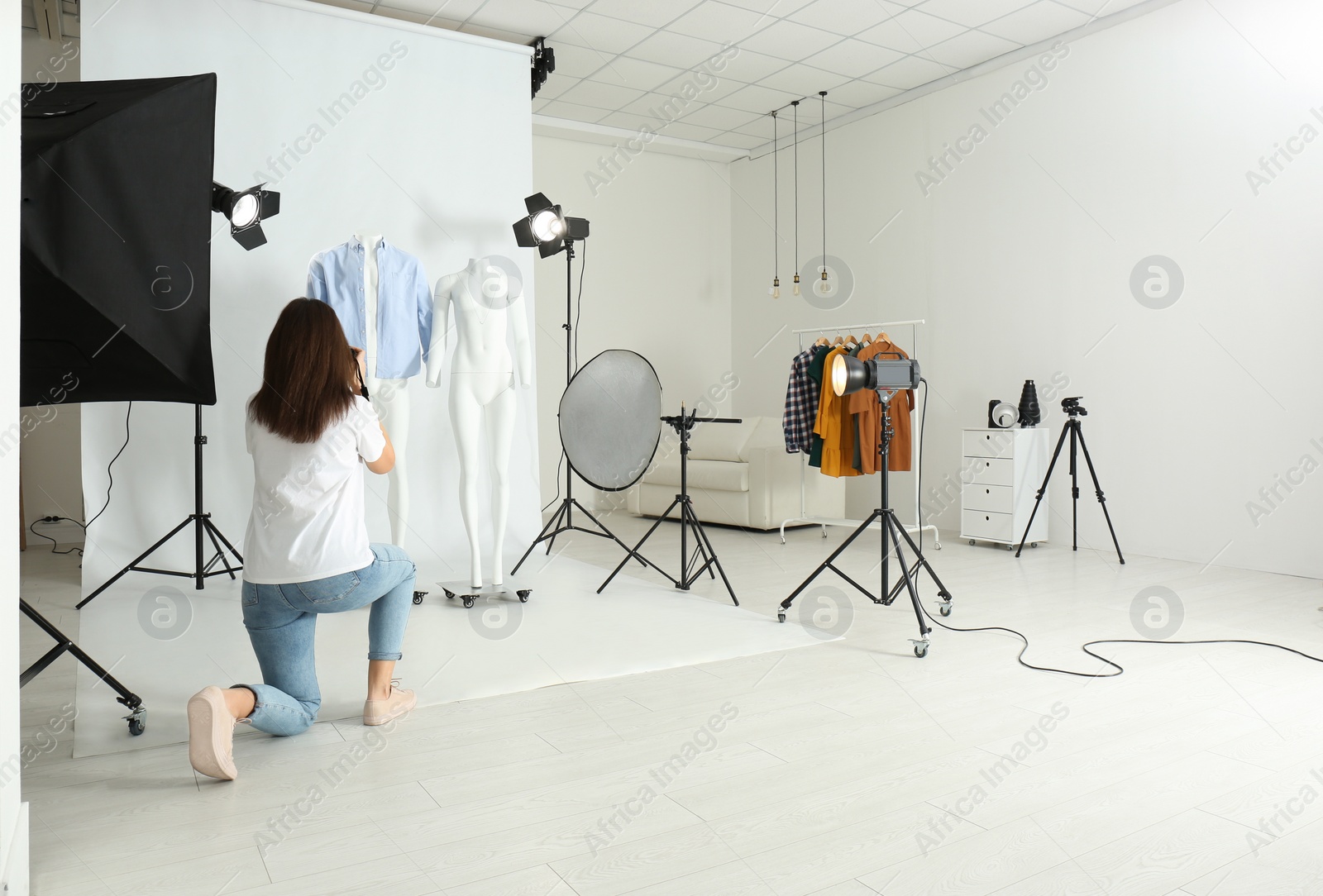 Photo of Professional photographer taking picture of ghost mannequins with modern clothes in photo studio