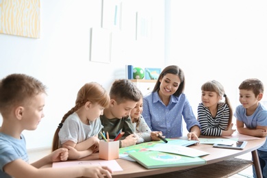 Photo of Cute little children with teacher in classroom at school