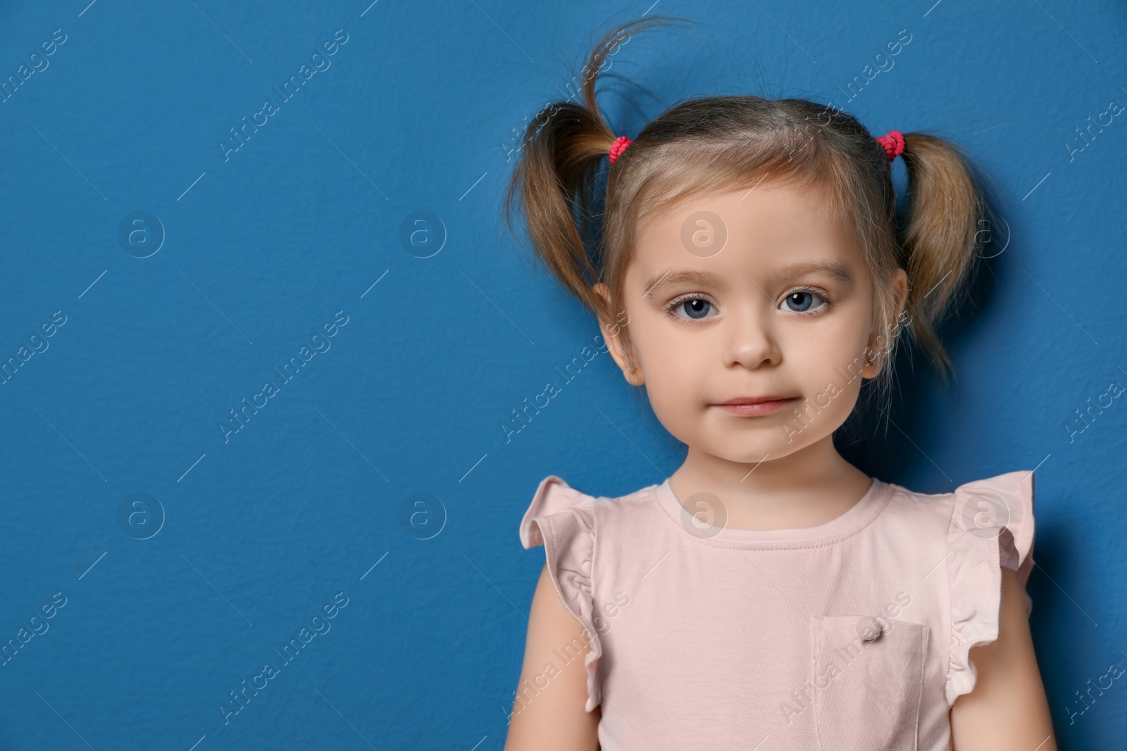 Photo of Portrait of cute little girl on blue background. Space for text